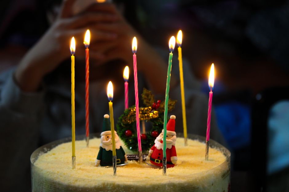 A beautifully decorated birthday cake with lit candles, surrounded by festive party decorations and warm lighting