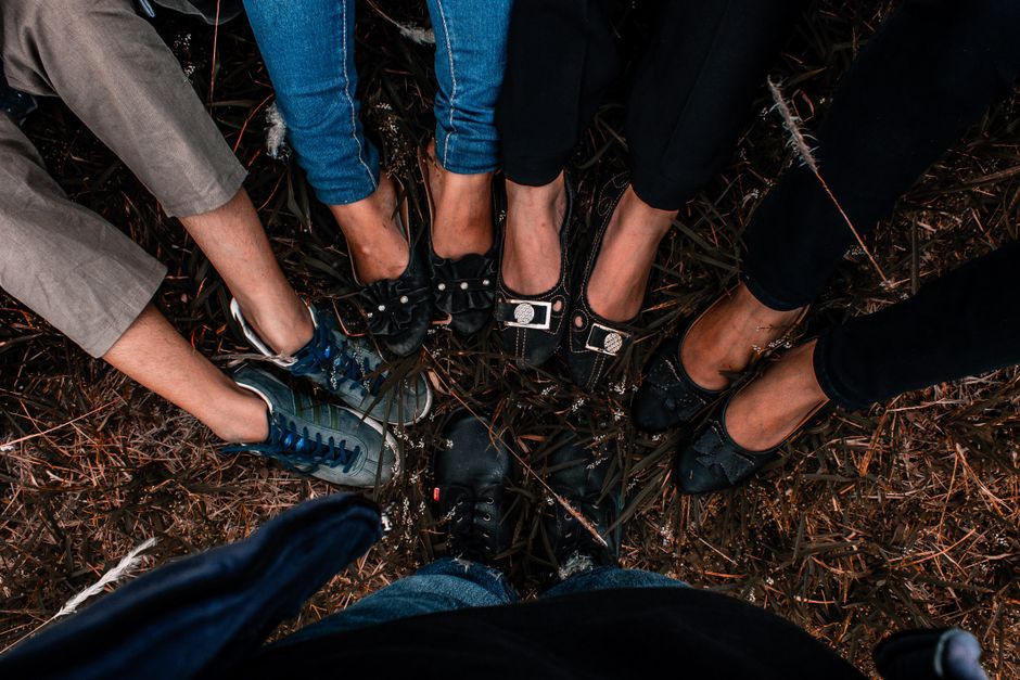 A group of friends laughing together at a backyard birthday party with warm overhead string lights