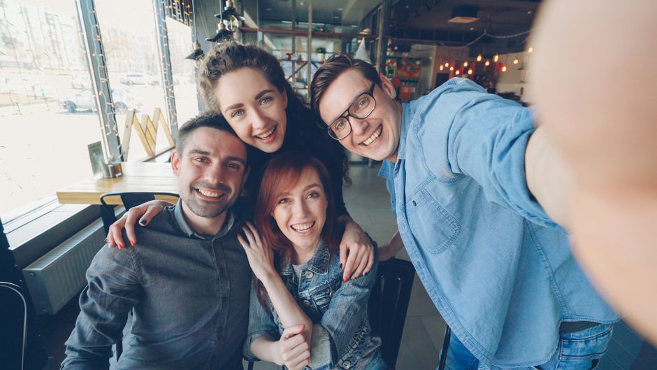 A smiling group of diverse people communicating using American Sign Language in a bright room