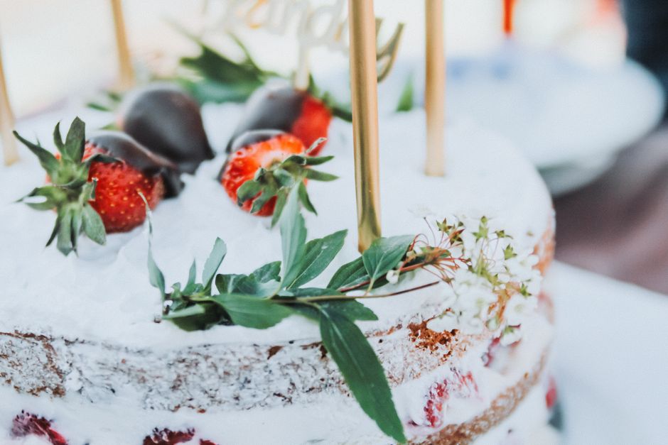 A traditional Norwegian birthday setup with a cream cake (bløtkake) decorated with fresh strawberries and small paper flags